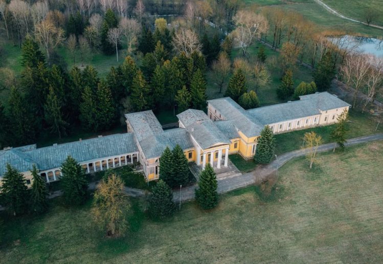 Drone shot of Rdułtowski Palace surrounded by lush countryside and forest in Snoŭ, Belarus.