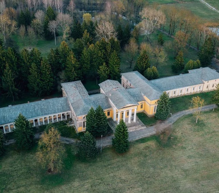 Drone shot of Rdułtowski Palace surrounded by lush countryside and forest in Snoŭ, Belarus.