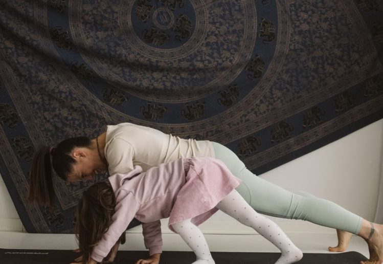A mother and child practicing yoga together indoors, showcasing family bonding and wellness.