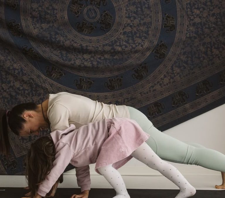 A mother and child practicing yoga together indoors, showcasing family bonding and wellness.